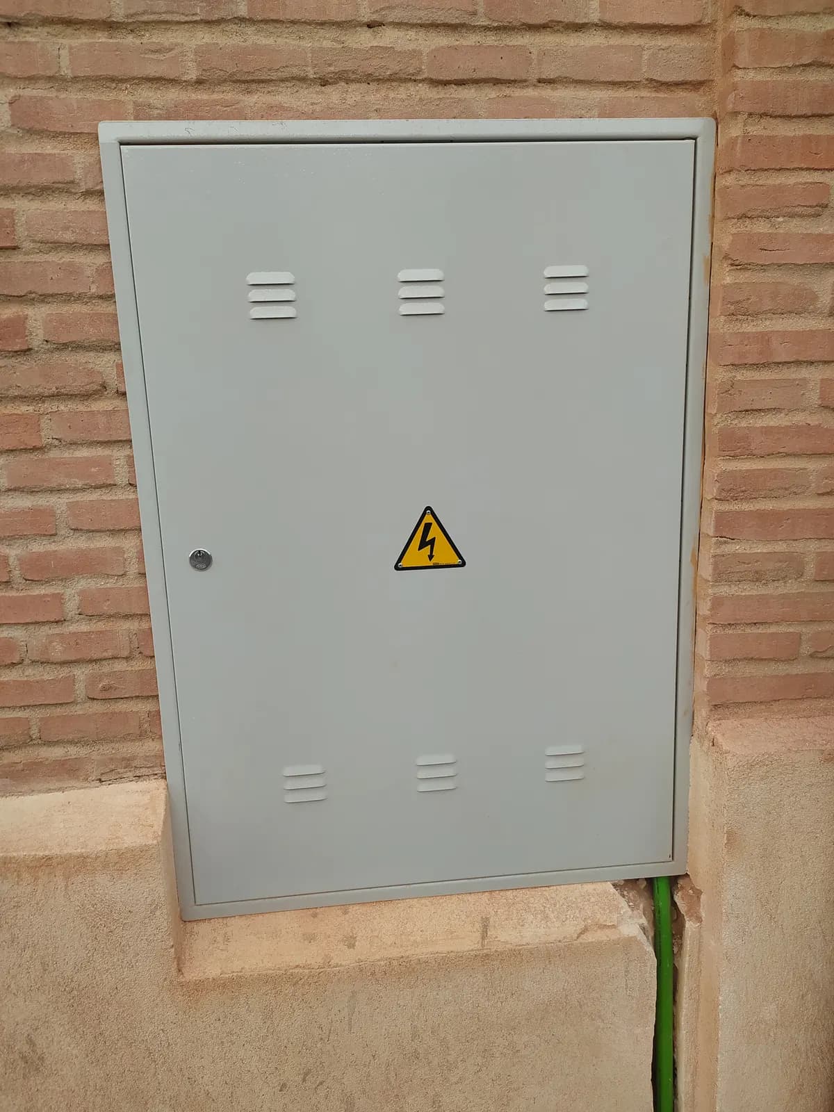 Weatherproof exterior electrical enclosure mounted on a brick wall