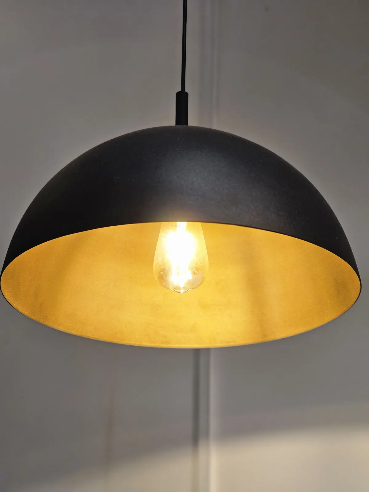 Modern black dome pendant light with a warm bulb glowing inside